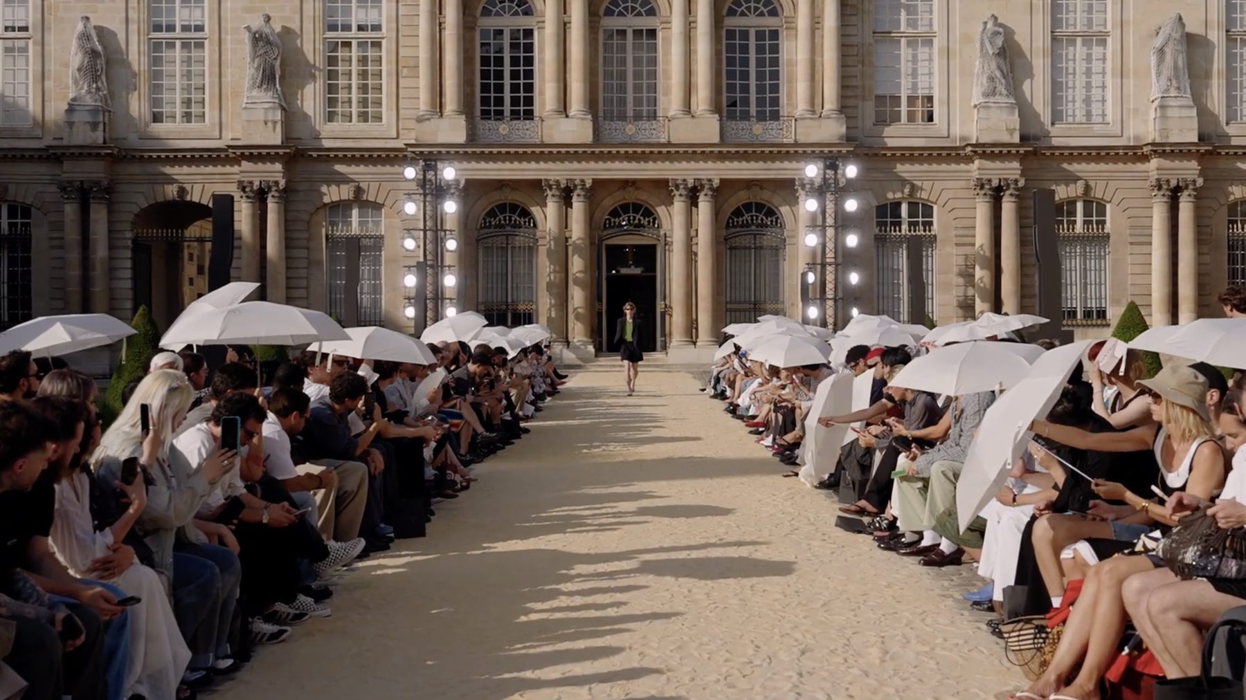 System Spring/Summer 2027 show, white parasols along a sand runway