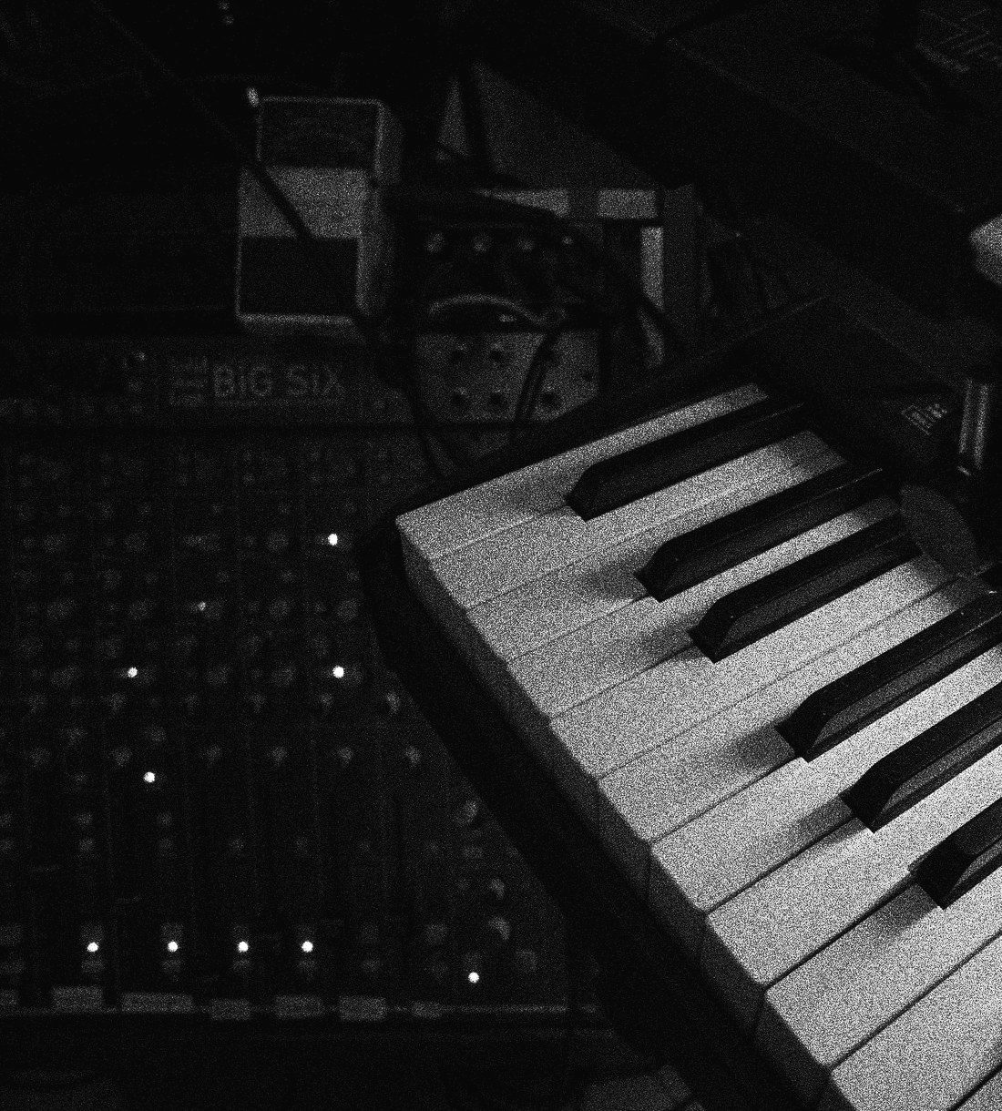 A keyboard resting above a mixing desk